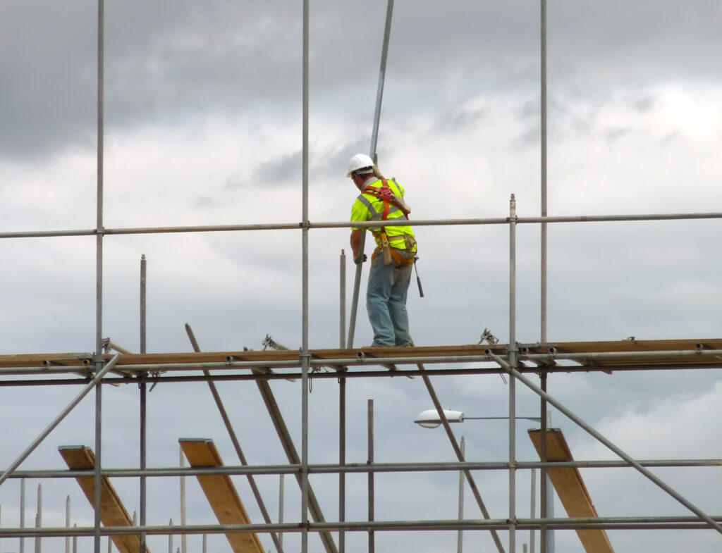 A worker on a highly elevated scaffold that has been inspected for scaffolding hazards.