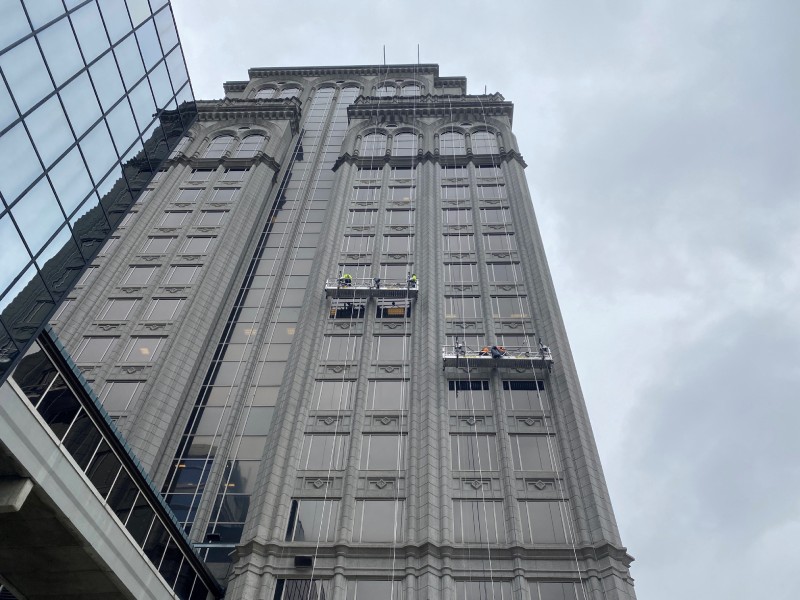 High-rise building with workers on suspended scaffolding cleaning exterior windows