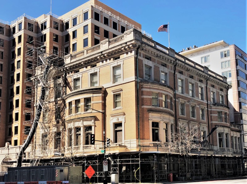 Extensive scaffolding system surrounding a multi-story building during exterior renovation and construction in an urban setting.