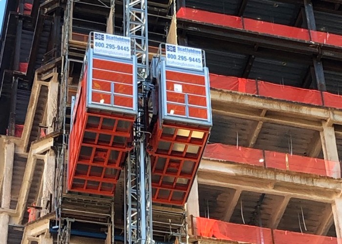 Dual construction hoists and suspended scaffolding on the exterior of a high-rise building during renovation.