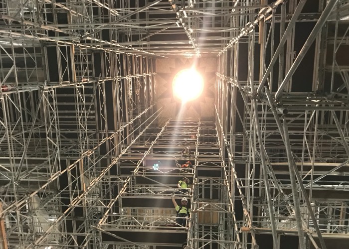 View from below showing workers on scaffolding inside a tall building under maintenance.